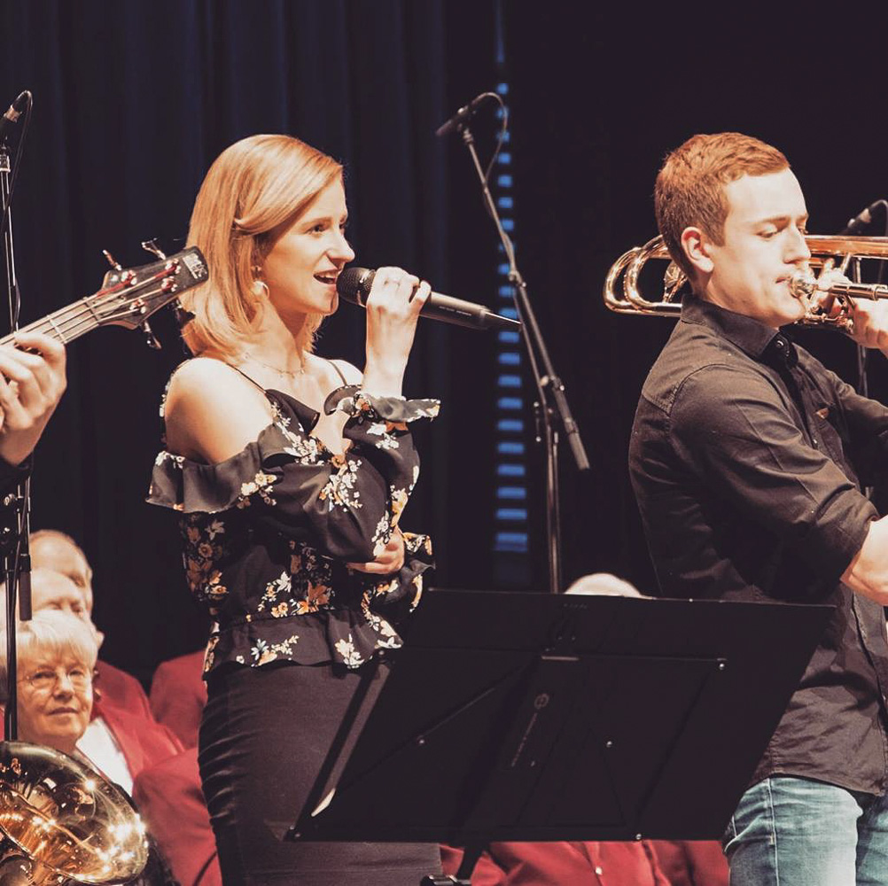 Sabrina Rammler singt mit einer Brass Band auf einer Bühne